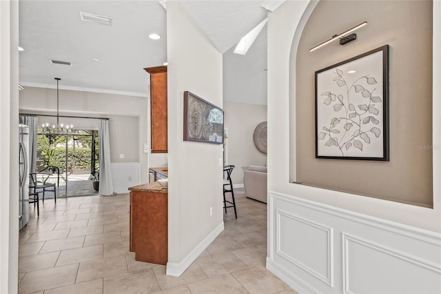 hall featuring ornamental molding, light tile patterned floors, and a notable chandelier