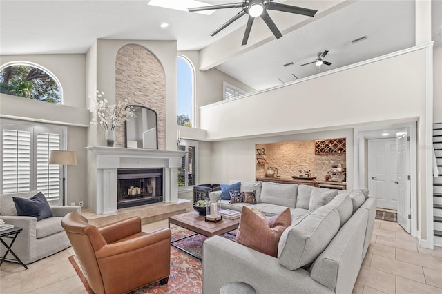 tiled living room with ceiling fan, beam ceiling, and high vaulted ceiling