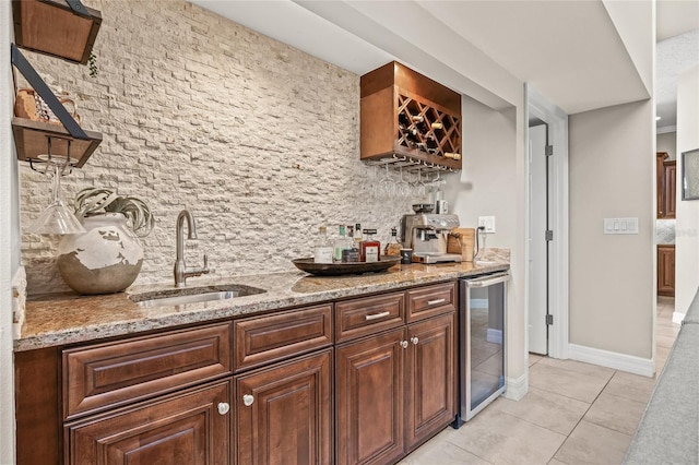 bar featuring sink, light stone counters, tasteful backsplash, light tile patterned floors, and beverage cooler