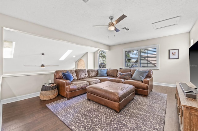 living room with lofted ceiling with skylight, dark hardwood / wood-style floors, and ceiling fan