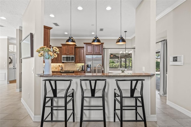 kitchen with appliances with stainless steel finishes, a breakfast bar, pendant lighting, backsplash, and dark stone counters