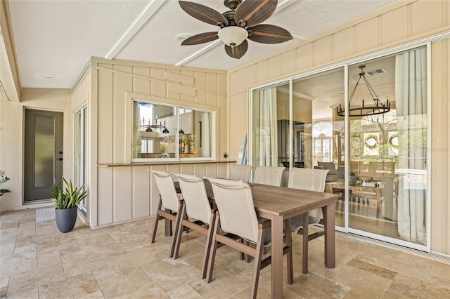 sunroom featuring ceiling fan with notable chandelier