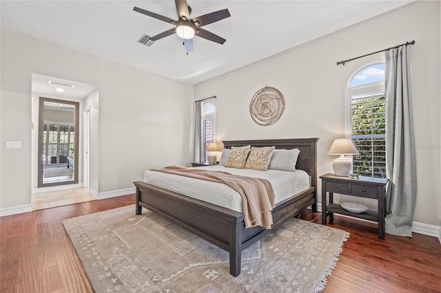 bedroom with multiple windows, dark hardwood / wood-style floors, and ceiling fan