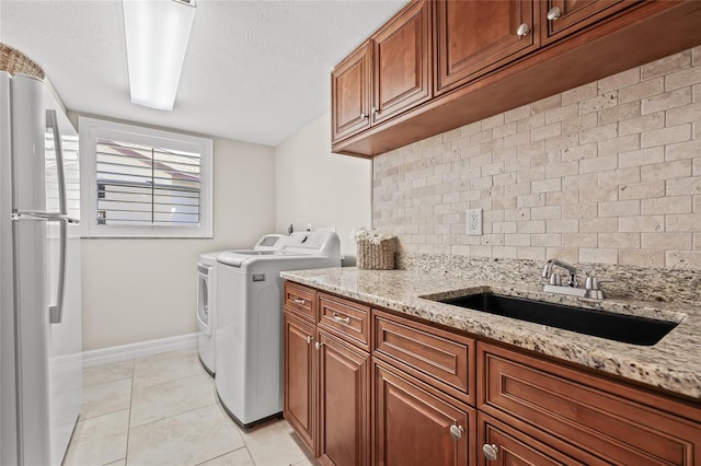 laundry room with sink, cabinets, a textured ceiling, washer and dryer, and light tile patterned floors