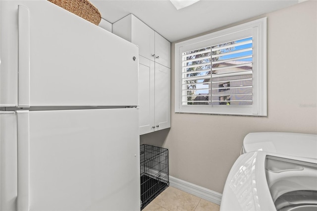 laundry area with light tile patterned flooring, cabinets, and washing machine and dryer