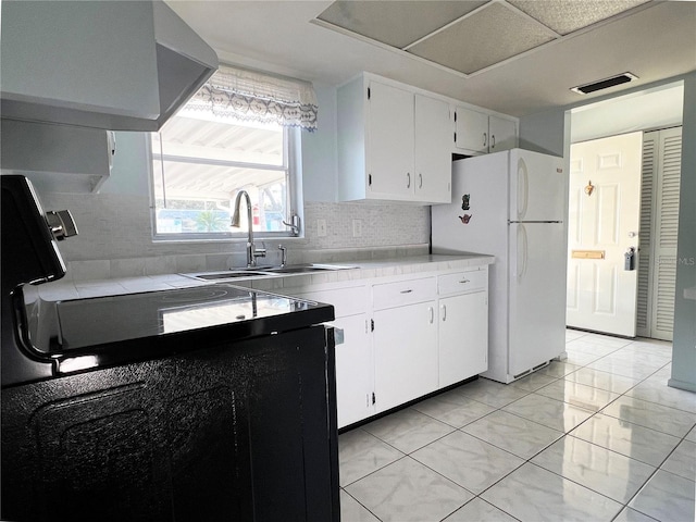 kitchen featuring white refrigerator, white cabinetry, sink, and backsplash