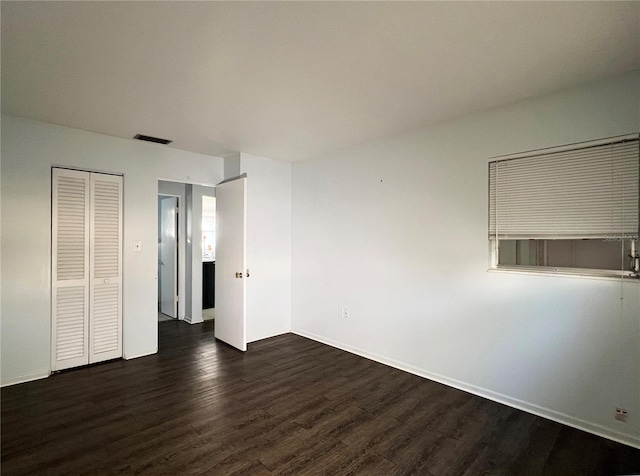 unfurnished bedroom featuring dark hardwood / wood-style flooring and a closet