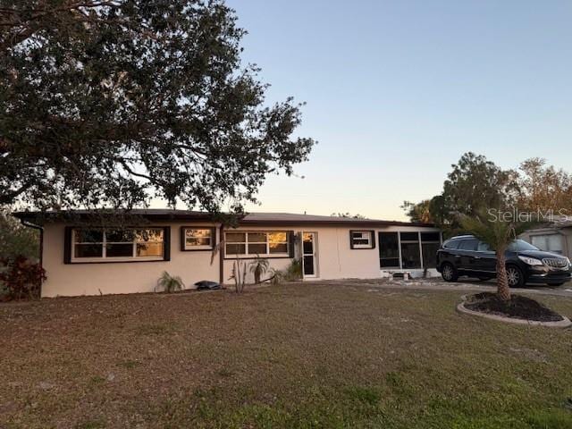 ranch-style house with stucco siding and a yard