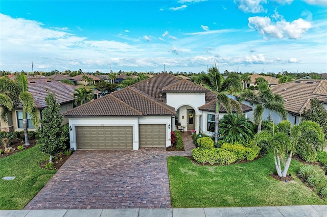 view of front facade with a garage, a tile roof, decorative driveway, and a front yard