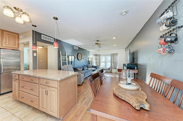 kitchen featuring ceiling fan, hanging light fixtures, a kitchen island, light brown cabinetry, and built in fridge