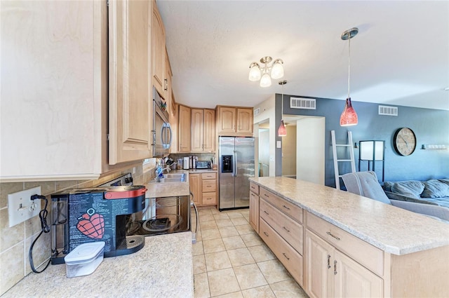 kitchen with light tile patterned floors, appliances with stainless steel finishes, hanging light fixtures, decorative backsplash, and light brown cabinets