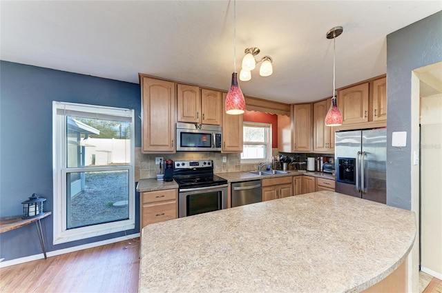 kitchen with stainless steel appliances, sink, backsplash, and decorative light fixtures