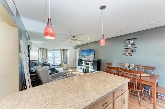 kitchen featuring light brown cabinetry, hanging light fixtures, ceiling fan, and light wood-type flooring