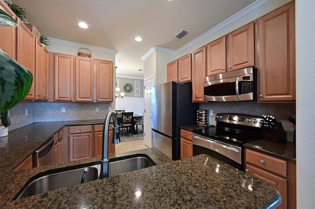 kitchen featuring sink, crown molding, dark stone countertops, backsplash, and stainless steel appliances