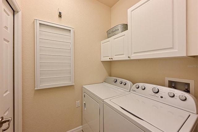 clothes washing area featuring cabinets and washer and clothes dryer