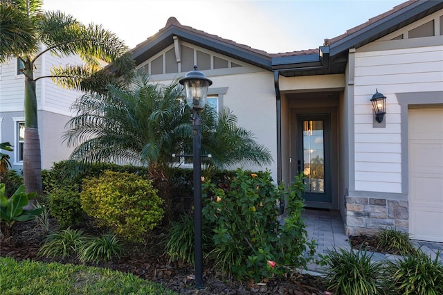 entrance to property with an attached garage and stone siding