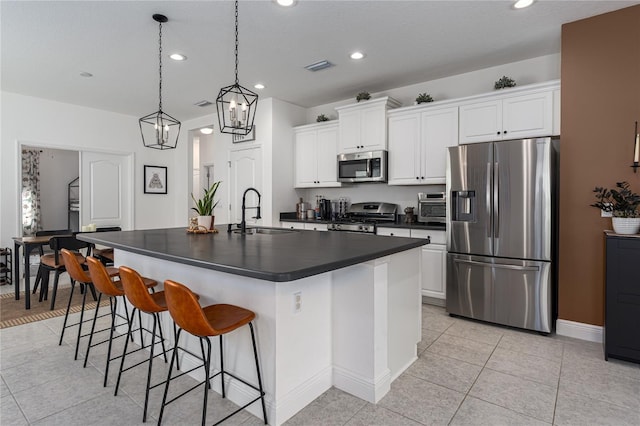 kitchen featuring pendant lighting, sink, appliances with stainless steel finishes, a kitchen island with sink, and white cabinetry