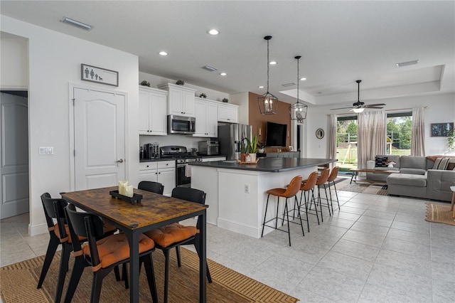 kitchen with a kitchen island, pendant lighting, white cabinetry, a kitchen bar, and stainless steel appliances