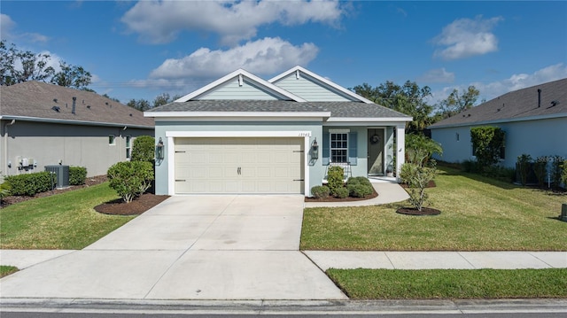 view of front of home with cooling unit, a garage, and a front lawn