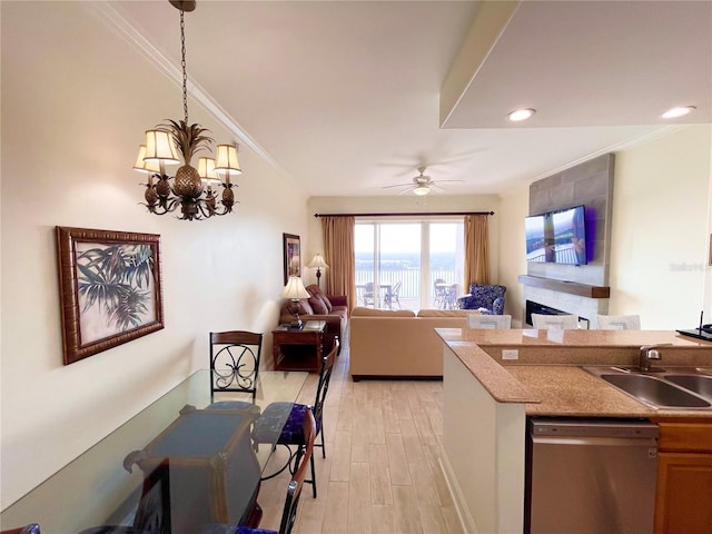 kitchen with open floor plan, crown molding, light wood-type flooring, stainless steel dishwasher, and a sink