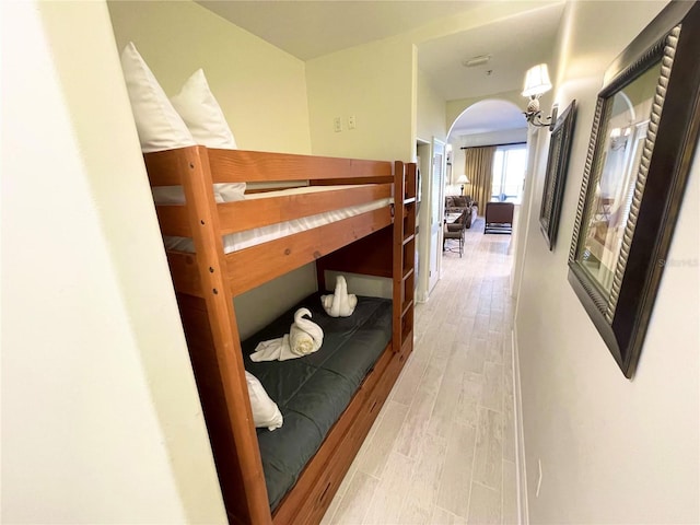 bedroom with light wood-style floors and arched walkways