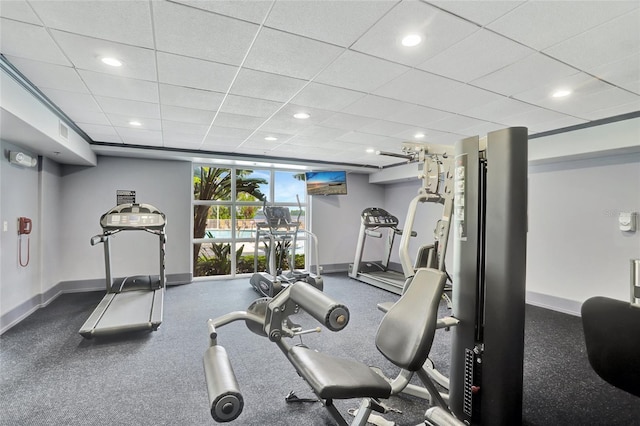 gym featuring a paneled ceiling, baseboards, and recessed lighting