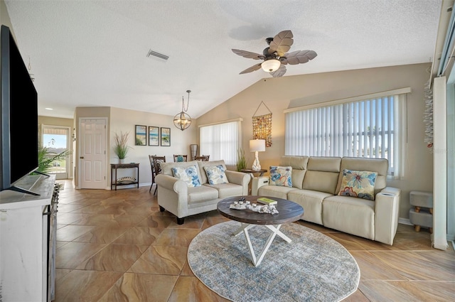 living room featuring ceiling fan with notable chandelier, vaulted ceiling, and a textured ceiling