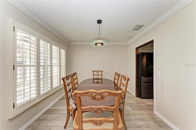 dining space with ornamental molding, light wood-style floors, visible vents, and a textured ceiling