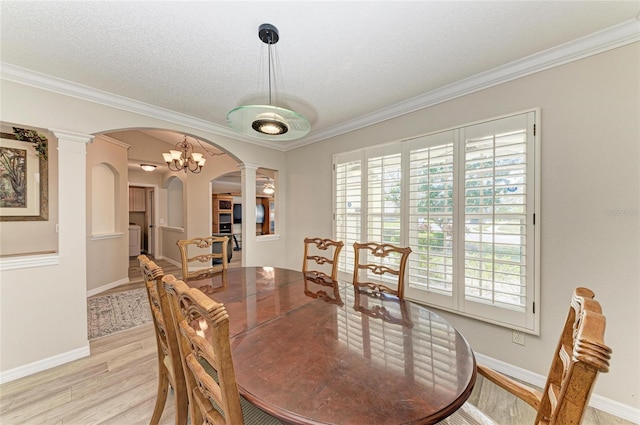 dining area with ornamental molding, light hardwood / wood-style floors, decorative columns, and a textured ceiling