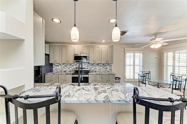 kitchen featuring a kitchen bar, backsplash, appliances with stainless steel finishes, and a peninsula