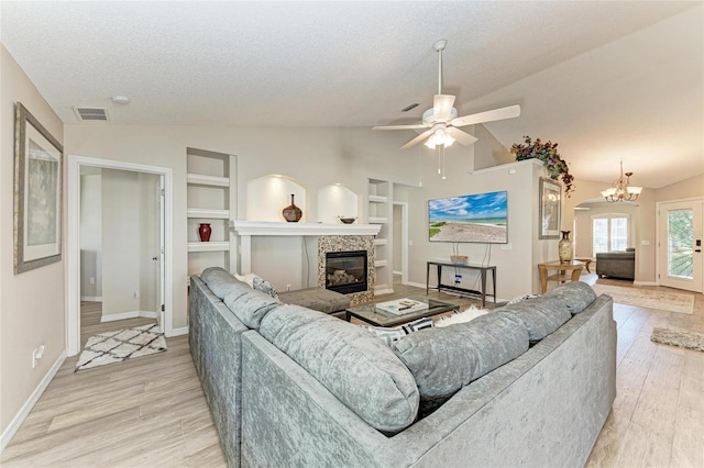 living area with light wood-type flooring, visible vents, a textured ceiling, lofted ceiling, and a tile fireplace