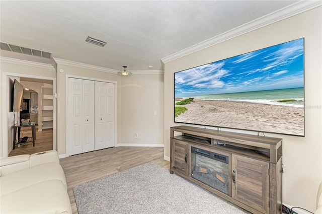 living room featuring visible vents, crown molding, baseboards, and wood finished floors