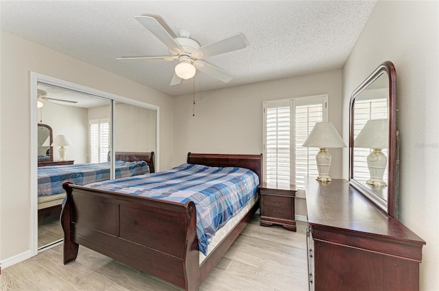 bedroom featuring ceiling fan, a closet, a textured ceiling, and light wood-type flooring