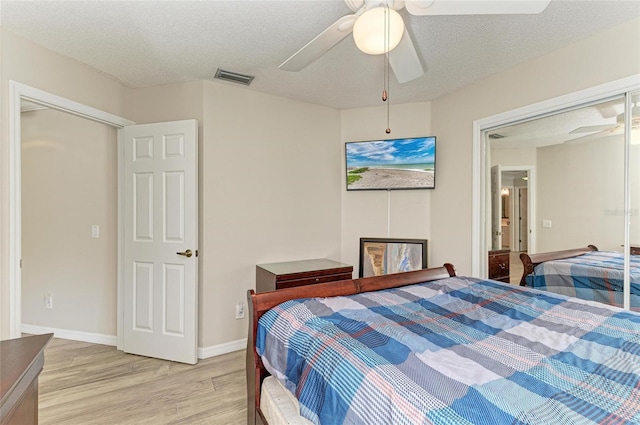 bedroom featuring ceiling fan, visible vents, light wood finished floors, and a textured ceiling