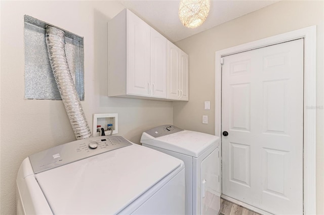 laundry area with cabinets, separate washer and dryer, and light wood-type flooring