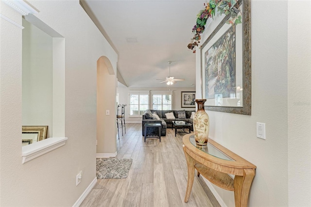 hall featuring baseboards, wood finished floors, visible vents, and arched walkways