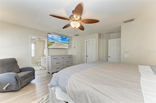 bedroom featuring visible vents, light wood-style flooring, a ceiling fan, a textured ceiling, and connected bathroom