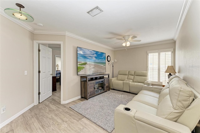 living area featuring visible vents, baseboards, ceiling fan, ornamental molding, and light wood-style floors