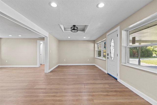 foyer entrance featuring a textured ceiling and light hardwood / wood-style floors