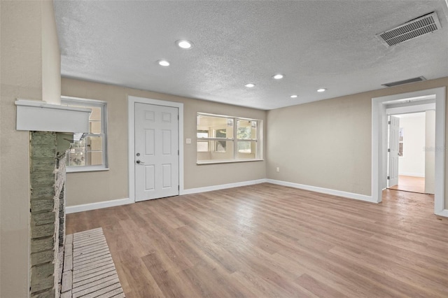 unfurnished living room featuring a textured ceiling and light hardwood / wood-style floors