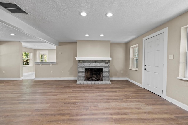 unfurnished living room featuring a fireplace, a textured ceiling, and light wood-type flooring