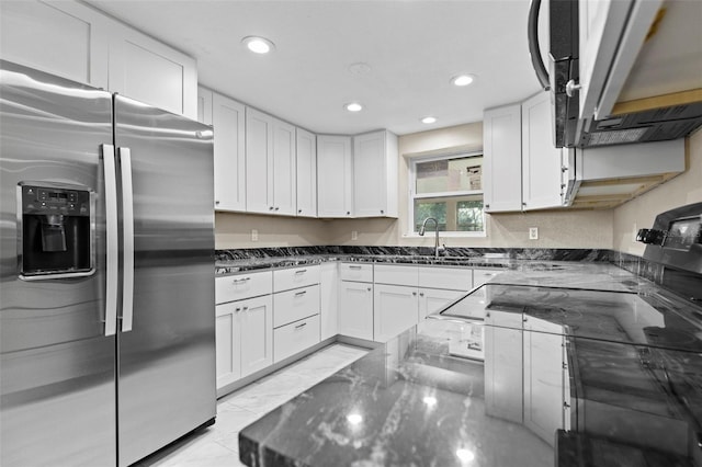 kitchen featuring white cabinetry, stainless steel appliances, and dark stone counters