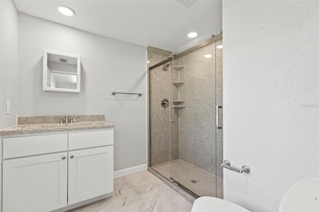 bathroom featuring vanity, toilet, a shower with door, and a textured ceiling