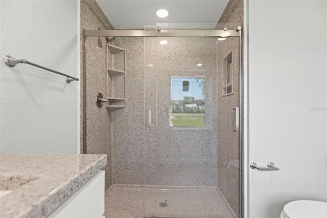 bathroom featuring vanity, an enclosed shower, and toilet