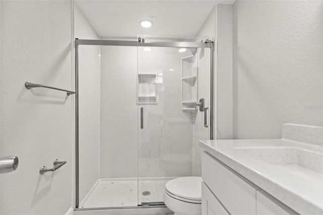 bathroom featuring vanity, a shower with shower door, and toilet