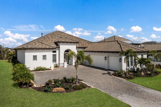 mediterranean / spanish-style home with a garage and a front lawn