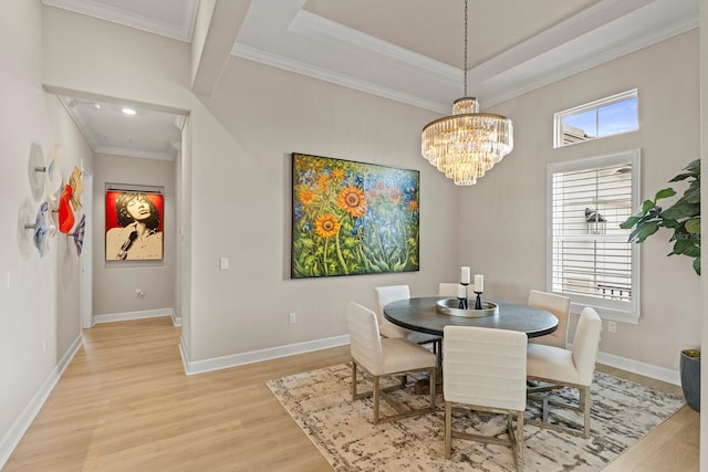 dining room featuring ornamental molding, a tray ceiling, a notable chandelier, and light hardwood / wood-style flooring