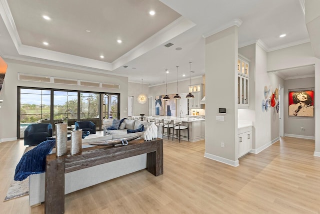 living room with crown molding, a raised ceiling, sink, and light hardwood / wood-style flooring