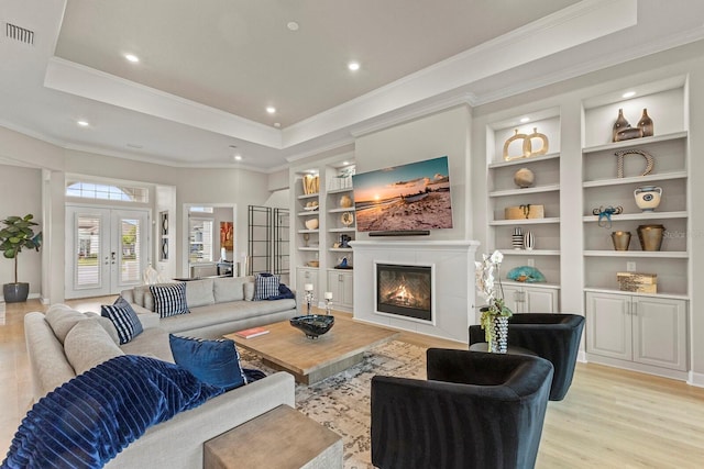 living room featuring a raised ceiling, light hardwood / wood-style flooring, and french doors