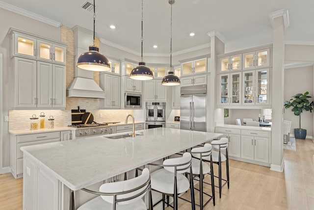 kitchen featuring an island with sink, pendant lighting, sink, and built in appliances